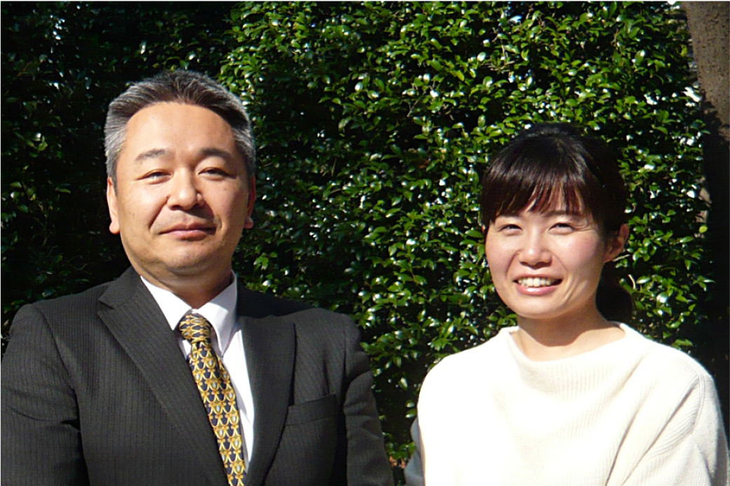 緑を背景に立つ、男女の写真